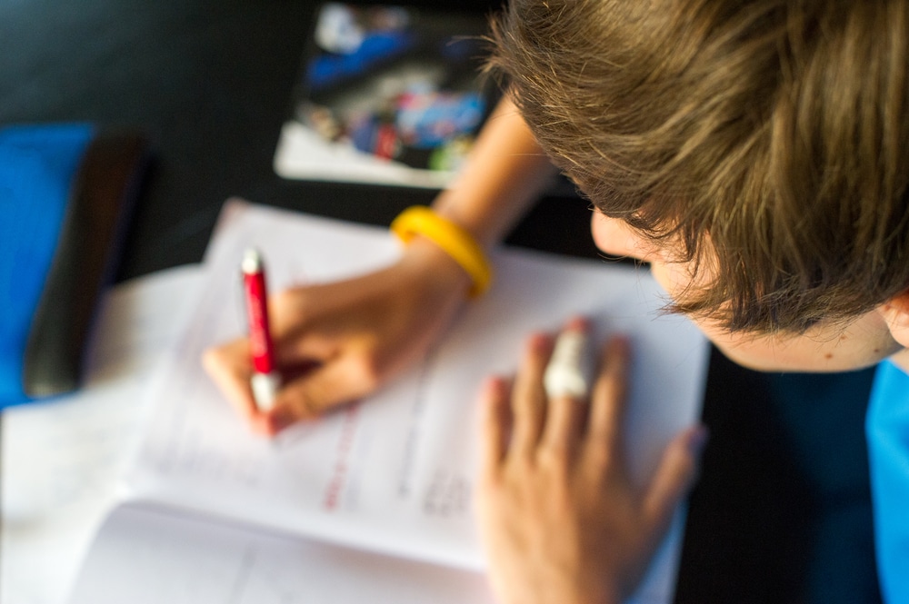 Young boy looking down and studying from a book.